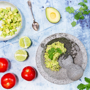 Guacamole in einem Mörser zubereitet dekoriert mit Tomaten und Limette 